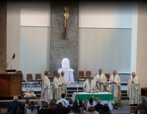 an image of seven priests concelebrating Holy Mass with a large congregation.